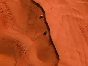 Stunning aerial shot of two cars making tracks on vibrant red sand dunes in a desert landscape. jigsaw puzzle