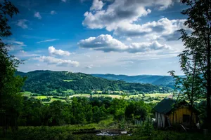 A picturesque countryside landscape featuring lush green hills under a bright blue sky. jigsaw puzzle