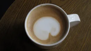 A top view of a frothy cappuccino in a ceramic cup placed on a wooden table. jigsaw puzzle