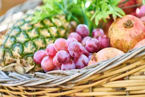 A colorful mix of fresh fruits including grapes, pineapple, and pomegranates in a wicker basket. jigsaw puzzle