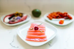Vibrant sliced salmon sashimi garnished with flowers on a white plate, perfect for gourmet dining. jigsaw puzzle