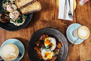 Top view of a delightful brunch spread featuring poached eggs and lattes on a wooden table. jigsaw puzzle