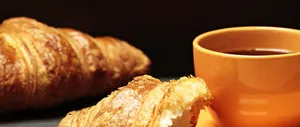 Close-up of a freshly baked croissant paired with a warm cup of coffee on a table. jigsaw puzzle