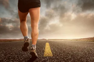 Runner's legs on a road during a sunset, symbolizing endurance and outdoor fitness training. jigsaw puzzle