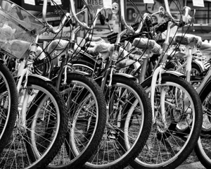 Black and white image of parked vintage bicycles on a street, highlighting spokes and handlebars. jigsaw puzzle