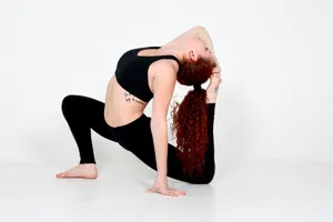 Woman in athletic wear performs an advanced yoga pose in a white studio setting. jigsaw puzzle