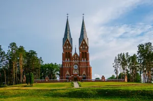 Explore the striking architecture of Viļaka's Roman Catholic Church set against a lush green landscape. jigsaw puzzle