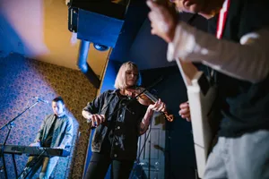 Musicians performing live with instruments like electric guitar, violin, and keyboard in a studio setting. jigsaw puzzle