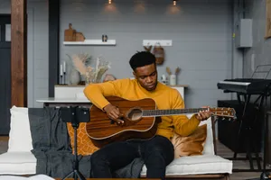 A young man playing acoustic guitar in a cozy home studio setting, perfect for music lovers. jigsaw puzzle