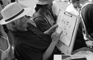Black and white photo of an artist sketching a portrait outdoors. Captures artistic creativity. jigsaw puzzle