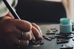 Detailed view of a hand using a brush to paint puzzle pieces, showcasing artistic creativity and precision. jigsaw puzzle