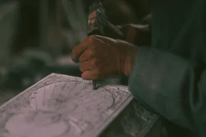 Close-up of a skilled artisan creating detailed art using hand tools on paper. jigsaw puzzle