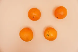 Four oranges arranged on a peach background, captured from above in a minimalist style. jigsaw puzzle