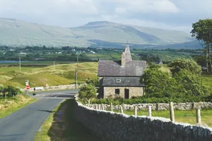 Stone building with steeple beside a country road. jigsaw puzzle