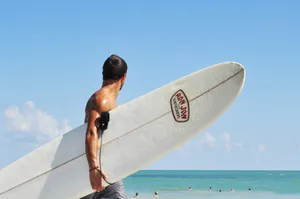 topless man carrying white surfboard in beach during daytime jigsaw puzzle