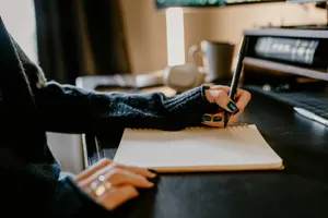 a person holding a pen and writing on a notebook jigsaw puzzle