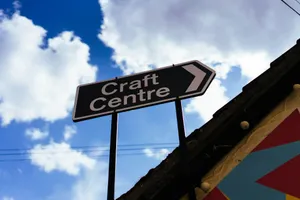 Black sign pointing right to craft centre under blue sky. jigsaw puzzle