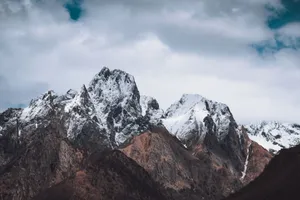 Snow-covered rocky mountains with a rugged profile under a cloudy sky, creating a dramatic landscape scene. jigsaw puzzle