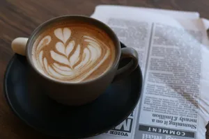 A cup of latte art placed on a newspaper, perfect for a cozy coffee break. jigsaw puzzle