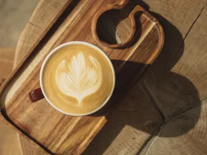 A latte with intricate leaf art served on a rustic wooden tray, perfect for cozy mornings. jigsaw puzzle
