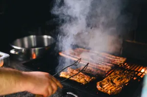 Close-up of grilling meat with smoke rising on a barbecue, outdoors. jigsaw puzzle