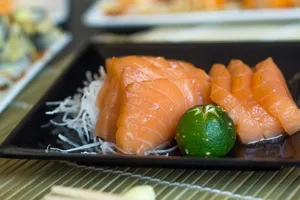 Close-up of fresh salmon sashimi served with calamansi on a black plate. jigsaw puzzle