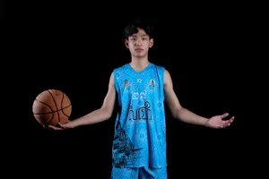 Young basketball player in vibrant blue uniform posing confidently with a basketball in a studio setting. jigsaw puzzle
