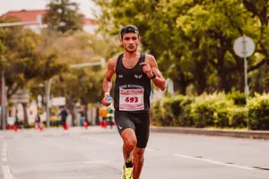 Focused male athlete running in a marathon, wearing a tank top and holding a bottle of water. jigsaw puzzle