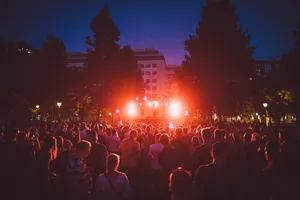 A lively outdoor EDM festival at night with a DJ and a vibrant crowd under colorful lights. jigsaw puzzle