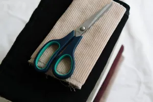Scissors placed on stacked corduroy fabric swatches ideal for sewing projects. jigsaw puzzle