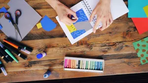 A vibrant arts and crafts setup with colorful papers and pastel colors on a wooden table. jigsaw puzzle