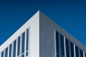 A modern building corner with large windows against a vibrant blue sky, showcasing minimalist architecture. jigsaw puzzle