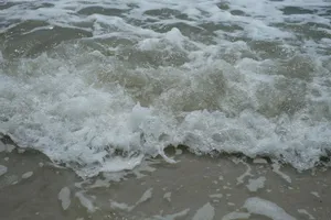 Close-up of gentle ocean waves crashing onto a sandy beach, capturing the essence of nature's beauty. jigsaw puzzle