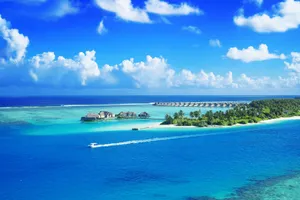 Crystal clear waters surround a luxurious Maldives resort under a bright blue sky. jigsaw puzzle