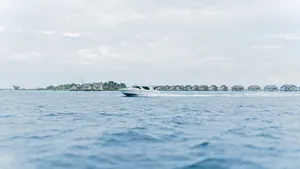 Tranquil scene of a speedboat cruising past overwater villas in the Maldives, under a serene sky. jigsaw puzzle