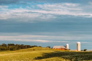 A serene rural scene featuring a barn and silos under a blue sky, perfect for farm-themed projects. jigsaw puzzle