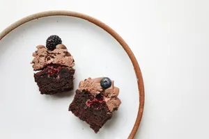 Close-up of two chocolate cupcakes with berry toppings on a simple ceramic plate. jigsaw puzzle