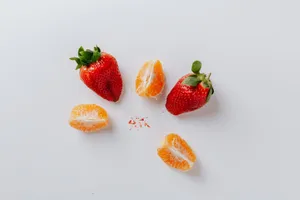 A minimalist flat lay of fresh strawberries and orange slices on a white background. jigsaw puzzle