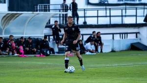 Soccer player dribbling during a match with team watching from the sidelines. jigsaw puzzle