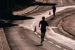 Silhouette of a runner on a street during a race. Captures athletic determination and movement. jigsaw puzzle
