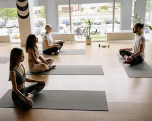 Four people meditating on yoga mats in a bright studio promoting wellness and relaxation. jigsaw puzzle