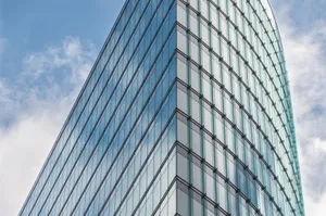 A sleek glass skyscraper reflecting the blue sky and clouds, showcasing modern architectural design. jigsaw puzzle