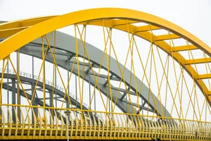 Close-up of modern bridge architecture featuring yellow and grey metal arches and railing. jigsaw puzzle