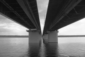 A modern bridge with a dramatic perspective over a calm river in black and white. jigsaw puzzle