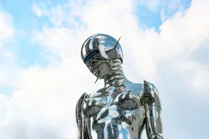 A sleek chrome robot sculpture stands against a bright blue sky background. jigsaw puzzle