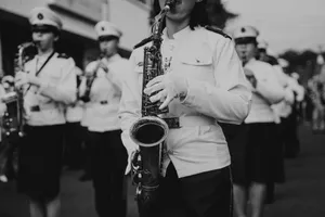 A black and white photo of a marching band performing in uniform during a parade. jigsaw puzzle