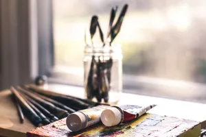 Sunlit table with art supplies, including brushes and paint tubes, ready for creative work. jigsaw puzzle