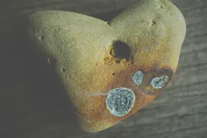 Close-up of a natural heart-shaped stone on a rustic wooden surface. jigsaw puzzle