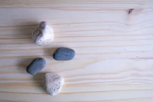 Four small stones placed on a light wood surface, showcasing natural textures and colors. jigsaw puzzle
