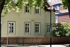 A light-colored house is behind a wooden fence. jigsaw puzzle